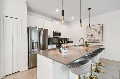 a kitchen with white cabinets and a counter with bar stools at 4BR Townhome Near Disney Water Park in Kissimmee