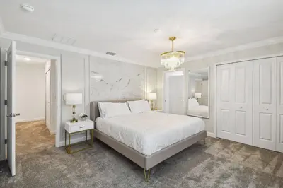 a white bedroom with a bed and a chandelier at 4BR Townhome Near Disney Water Park in Kissimmee