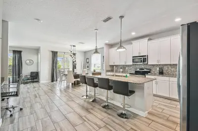 an open kitchen and dining room with white cabinets at Luxury Family Retreat Near Disney in Kissimmee