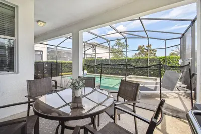 a patio with a table and chairs and a pool at Luxury Family Retreat Near Disney in Kissimmee