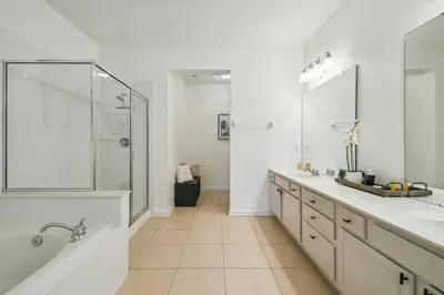 a white bathroom with two sinks and a shower at Orlando Stay Near Universal Studios in Orlando