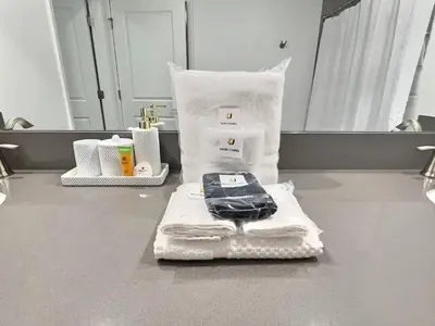 a pile of towels and a cell phone on a bathroom counter at Orlando Luxury Stay Near Disney Parks in Kissimmee