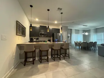 a kitchen and living room with a counter and chairs at Orlando Luxury Stay Near Disney Parks in Kissimmee