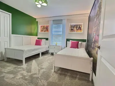 two beds in a room with green walls and pink pillows at Orlando Luxury Stay Near Disney Parks in Kissimmee