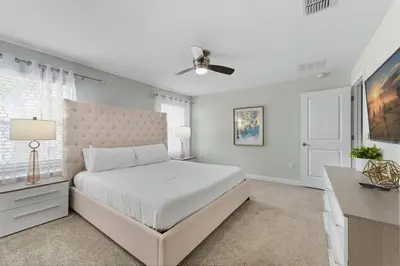 a white bedroom with a bed and a ceiling fan at Orlando Stay Near Disney with Private Pool in Kissimmee