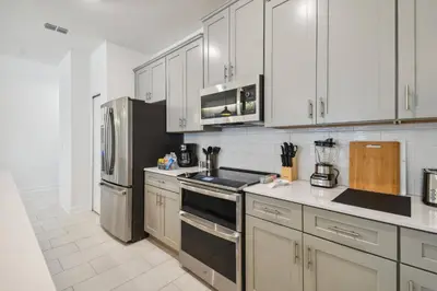 a kitchen with white cabinets and stainless steel appliances at Orlando Getaway – Minutes to Disney Parks in Kissimmee
