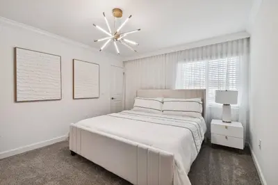 a white bedroom with a large bed and a chandelier at Disney Getaway: Private Pool Resort in Kissimmee