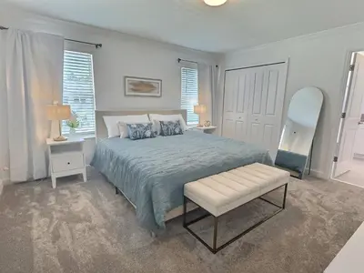 a bedroom with a bed and a chair and windows at Luxury Home Near Disney Orlando in Kissimmee