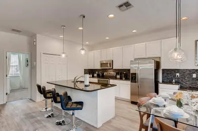 a kitchen with white cabinets and a table with chairs at Family Townhome w Private Pool Orlando in Kissimmee