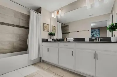 a bathroom with white cabinets and a large mirror at Heated Pool 5-Star Amenities Near Disney in Kissimmee