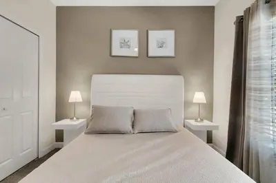 a bedroom with a white bed with two lamps at Heated Pool 5-Star Amenities Near Disney in Kissimmee