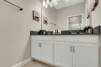 a white bathroom with a sink and a mirror at Heated Pool 5-Star Amenities Near Disney in Kissimmee