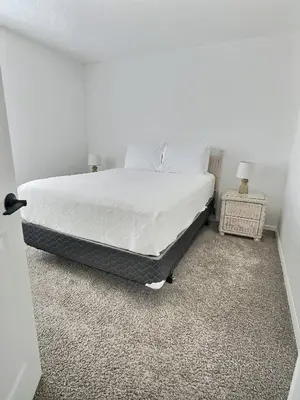 a bedroom with a bed with white sheets and two lamps at Family Villa near Disney – 15 Min in Kissimmee