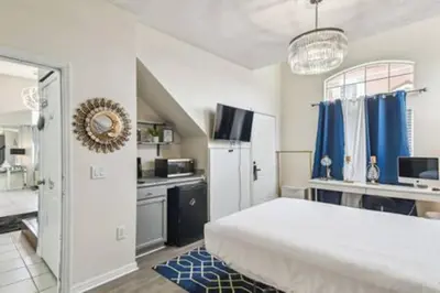 a bedroom with a large white bed and a kitchen at Resort Townhome · Sleeps 8 · Pool in Kissimmee