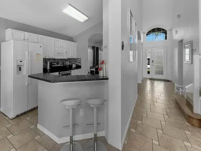a kitchen with white cabinets and a counter and stools at Spacious Home · Near Disney Parks in Kissimmee