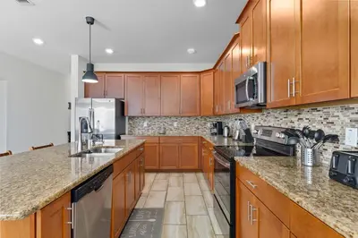 a kitchen with wooden cabinets and stainless steel appliances at Spacious 6BR Pool Resort - Near Disney in Kissimmee