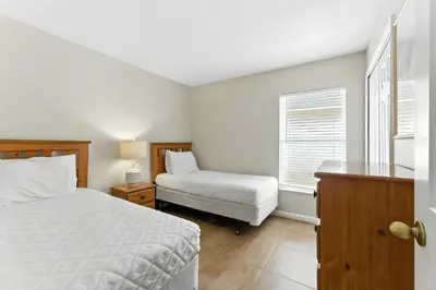a white bedroom with a bed and a window at Cozy No-Carpet Home Heated Pool Disney in Kissimmee