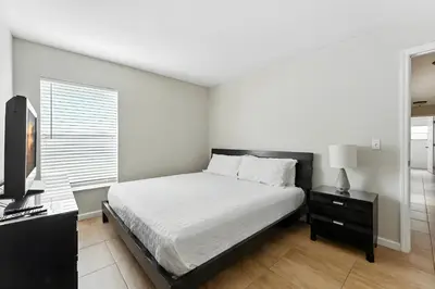 a bedroom with a bed and a desk and a television at Cozy No-Carpet Home Heated Pool Disney in Kissimmee