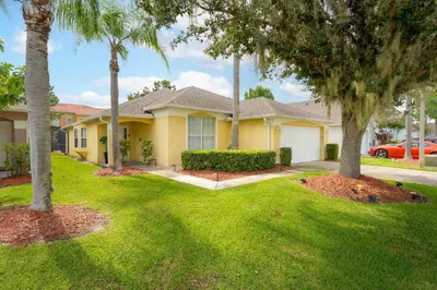 a house with palm trees in a yard at Two Master Suites Private Pool in Kissimmee