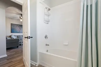 a bathroom with a tub and a shower curtain at 3BR Windsor Hills Condo Water Park and Skeeball Near Disney No Resort Fees in Orlando