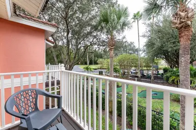 a chair on a balcony with palm trees at Family Townhouse 10 Min to Parks with Themed Room in Kissimmee