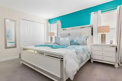 a bedroom with a white bed with a blue wall at Townhouse 4Q em Storey Lake – 10 min da Disney in Kissimmee