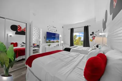 a white bedroom with two beds with red pillows at 2 Bedroom Deluxe - Theme Park in Orlando