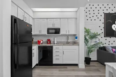 a kitchen with white cabinets and a black refrigerator at 2 Bedroom Deluxe - Theme Park in Orlando