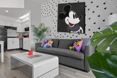 a living room with a gray couch and a mickey wall at 2 Queen Beds Theme Park in Orlando