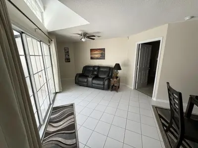 a living room with a black leather couch and a window at Villa Crayson home in Kissimmee