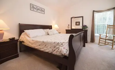 a bedroom with a bed and a mirror and a chair at Cumbrian Retreat home in Kissimmee