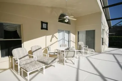 a patio with chairs and a table and a clock at Cumbrian Retreat home in Kissimmee
