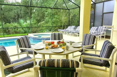 a table and chairs on a patio next to a pool at Weikva Villa home in Kissimmee