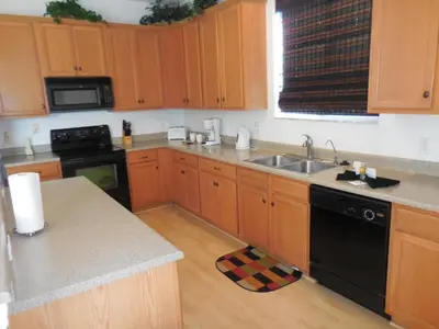 a kitchen with wooden cabinets and a sink and a stove at Berkeley Pool Home home in Kissimmee
