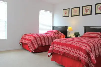 two beds in a bedroom with red blankets at Berkeley Pool Home home in Kissimmee