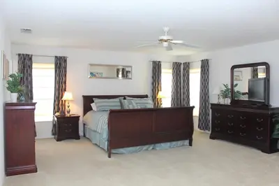 a bedroom with a bed and a mirror and a tv at Berkeley Pool Home home in Kissimmee