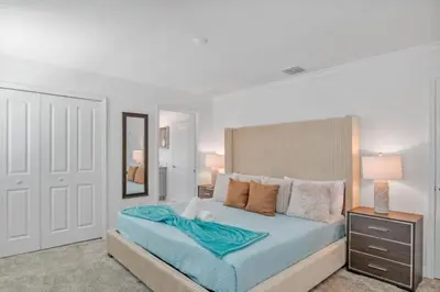 a white bedroom with a large bed with blue sheets at Top House with Private Pool and Resort in Kissimmee