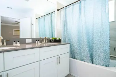 a bathroom with white cabinets and a blue shower curtain at Casa 4Q Storey Lake c/ Quarto Temático & Piscina in Kissimmee