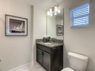 a bathroom with a toilet and a sink and a mirror at 3065 - 5BR w Pool 10min Disney 2 Water Parks in Kissimmee