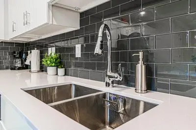 a kitchen with a stainless steel sink and black tiles at 3121#308- 3BR Condo 10min Disney 2 WaterParks in Kissimmee