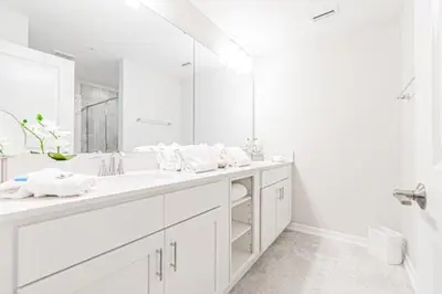 a white bathroom with two sinks and a large mirror at 3121#308- 3BR Condo 10min Disney 2 WaterParks in Kissimmee