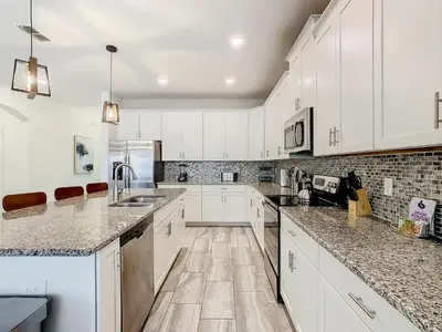 a kitchen with white cabinets and marble counter tops at 4774 - 7BR w Pool 10min Disney 2 Water Parks in Kissimmee