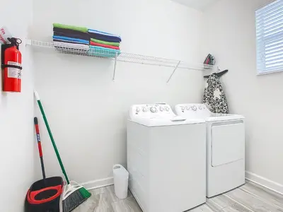 a laundry room with a washing machine and a broom at 4774 - 7BR w Pool 10min Disney 2 Water Parks in Kissimmee