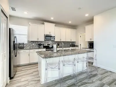 a kitchen with white cabinets and marble counter tops at 4781 - 5BR w Pool 10min Disney 2 Water Parks in Kissimmee