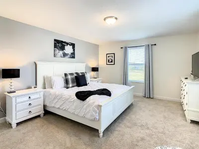 a bedroom with a white bed and a tv at 4809 - 5BR w Pool 10min Disney 2 Water Parks in Kissimmee