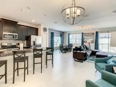 a kitchen and living room with a couch and chairs at 4874 - 5BR w Pool 10min Disney 2 Water Parks in Kissimmee