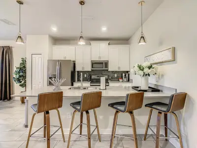 a kitchen with a large island with four chairs at 4916 - 5BR w Pool 10min Disney 2 Water Parks in Kissimmee