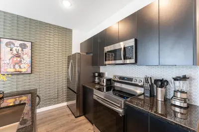 a kitchen with stainless steel appliances and black cabinets at Family 3BR Home Minutes from Disney in Kissimmee