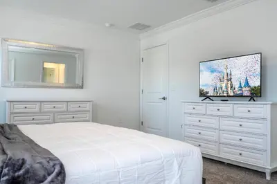 a white bedroom with a bed and a tv at 4BR Pool Home at Storey Lake Near Disney in Kissimmee