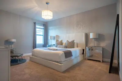 a bedroom with a large bed and a chandelier at 6BR Home w Theater Pool Near Disney in Orlando